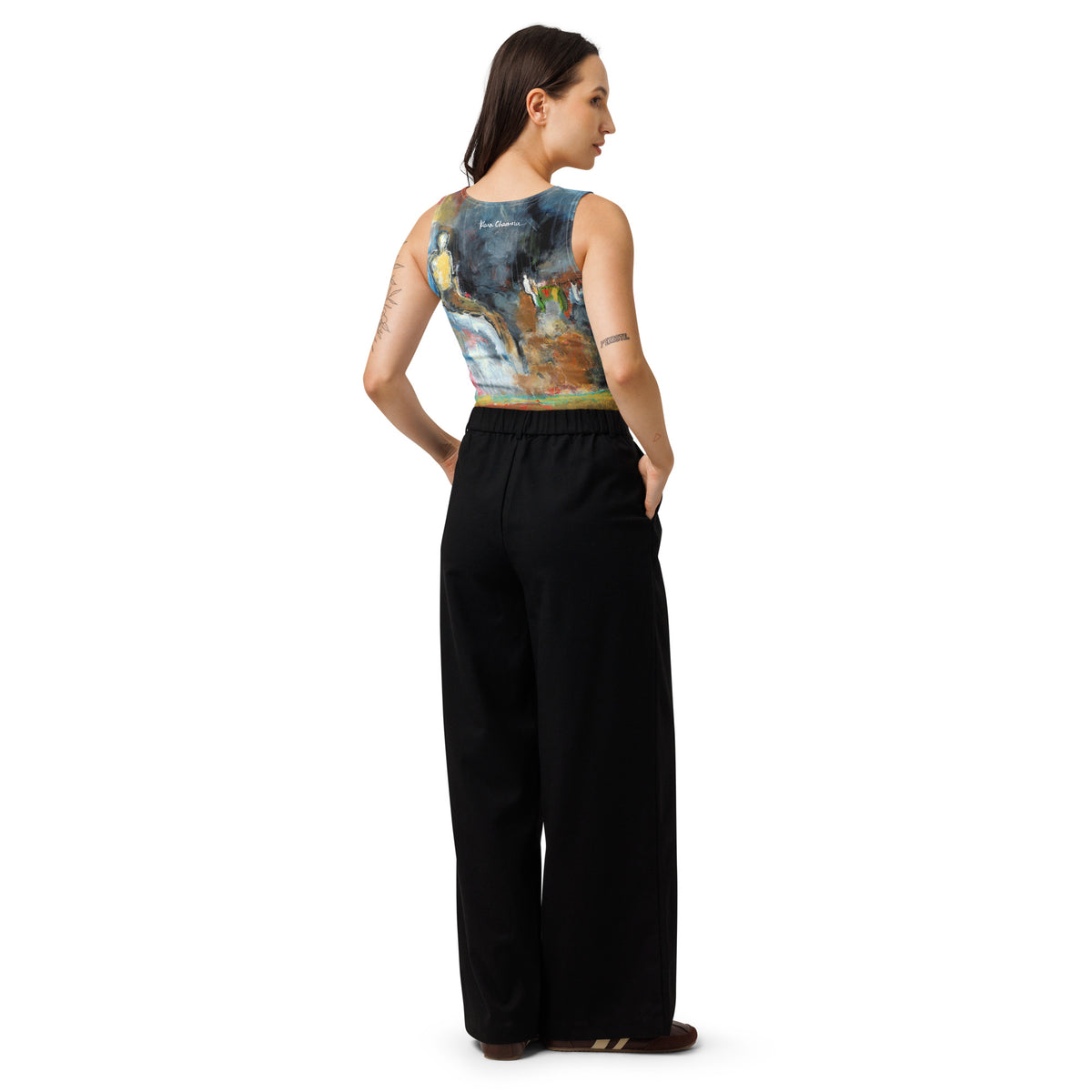 Back view of model in the crop top and black wide-leg pants, hand in pocket, looking aside