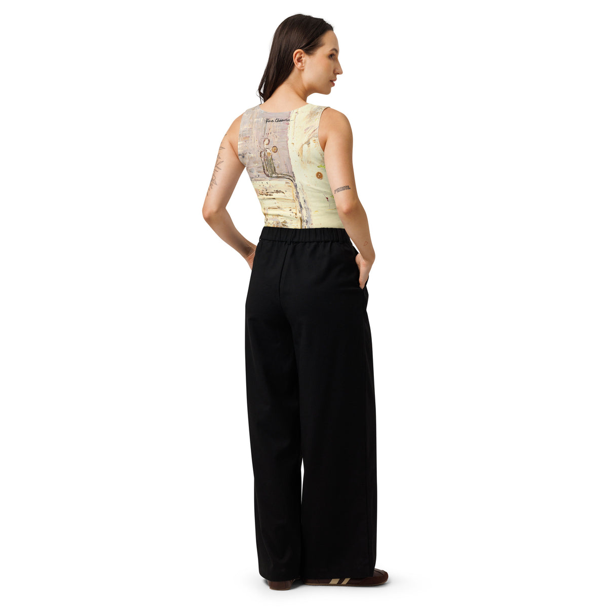 Back view of model in the crop top and black trousers, signature at the neckline above the seated figure print