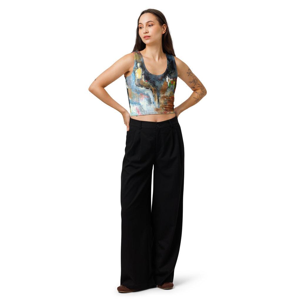 Model in the blue, ochre and gray crop top and black trousers, both hands on hips
