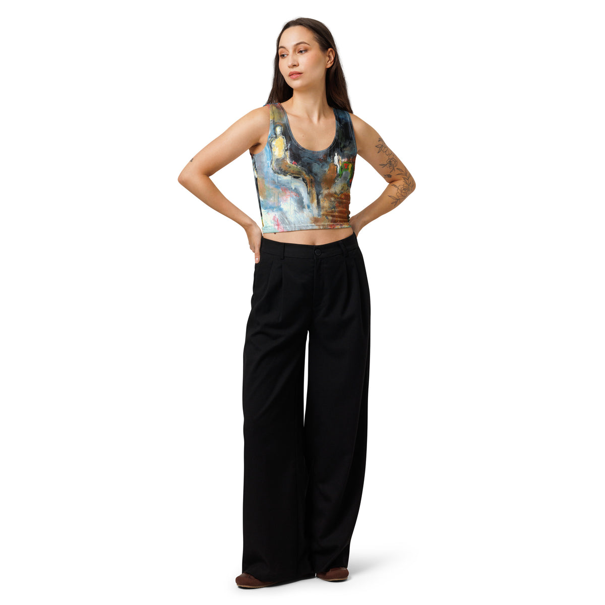 Model in the blue, ochre and gray crop top and black trousers, both hands on hips