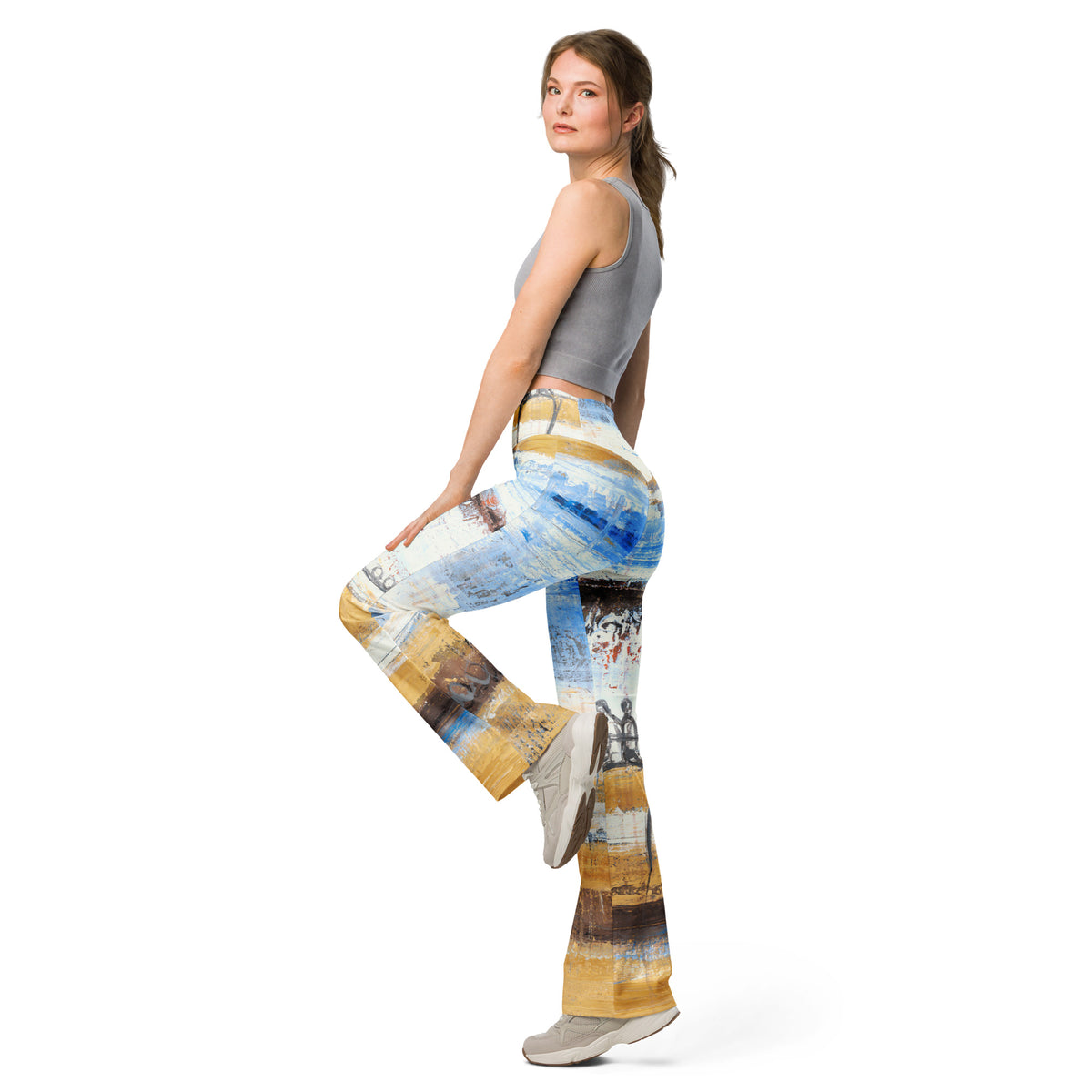Model in a gray crop tank balancing on one leg in the flare leggings, painted bands in motion
