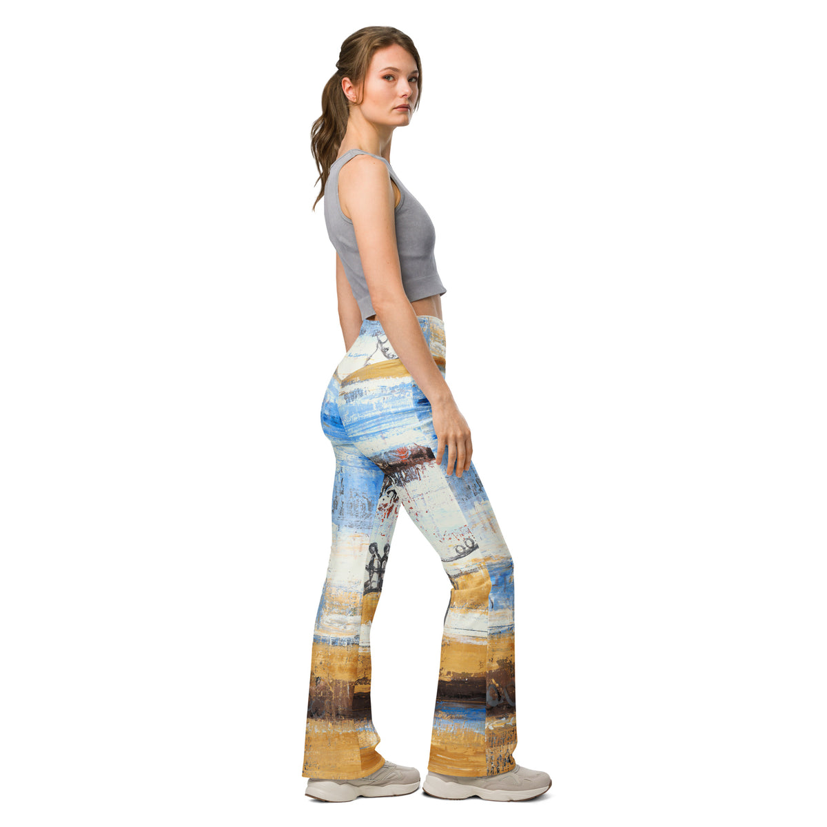 Model in a gray crop tank looking over her shoulder in the blue and ochre flare leggings