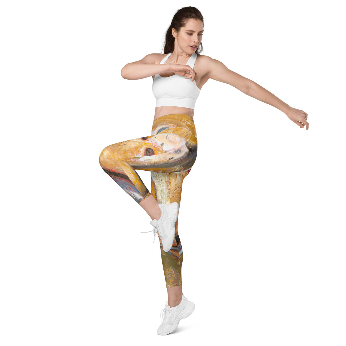 Model in a white sports bra lifting one knee with arms outstretched in the leggings