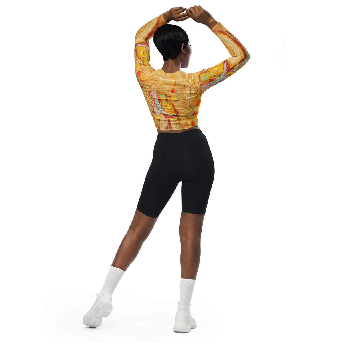 Back view of model with hands clasped above her head, crop top and black bike shorts
