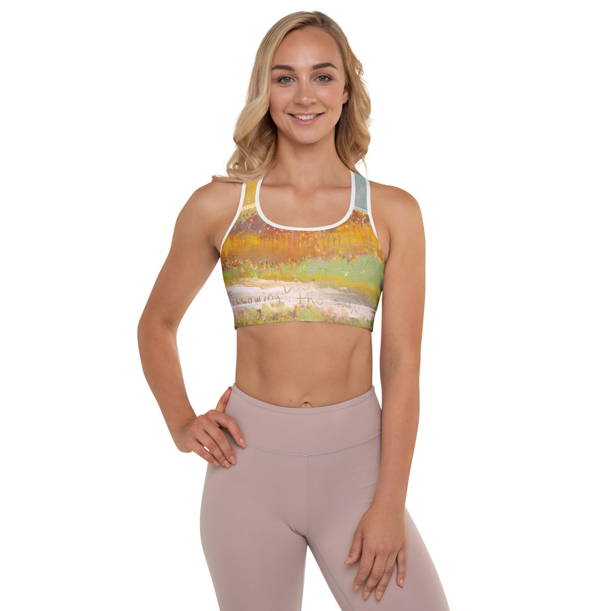 Smiling blonde model facing forward, hand on hip, in the sports bra and mauve leggings