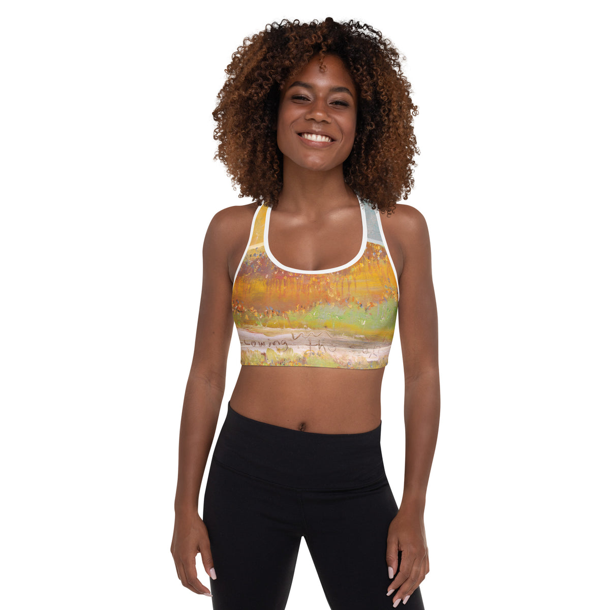 Smiling model with curly hair facing forward in the sports bra and black leggings