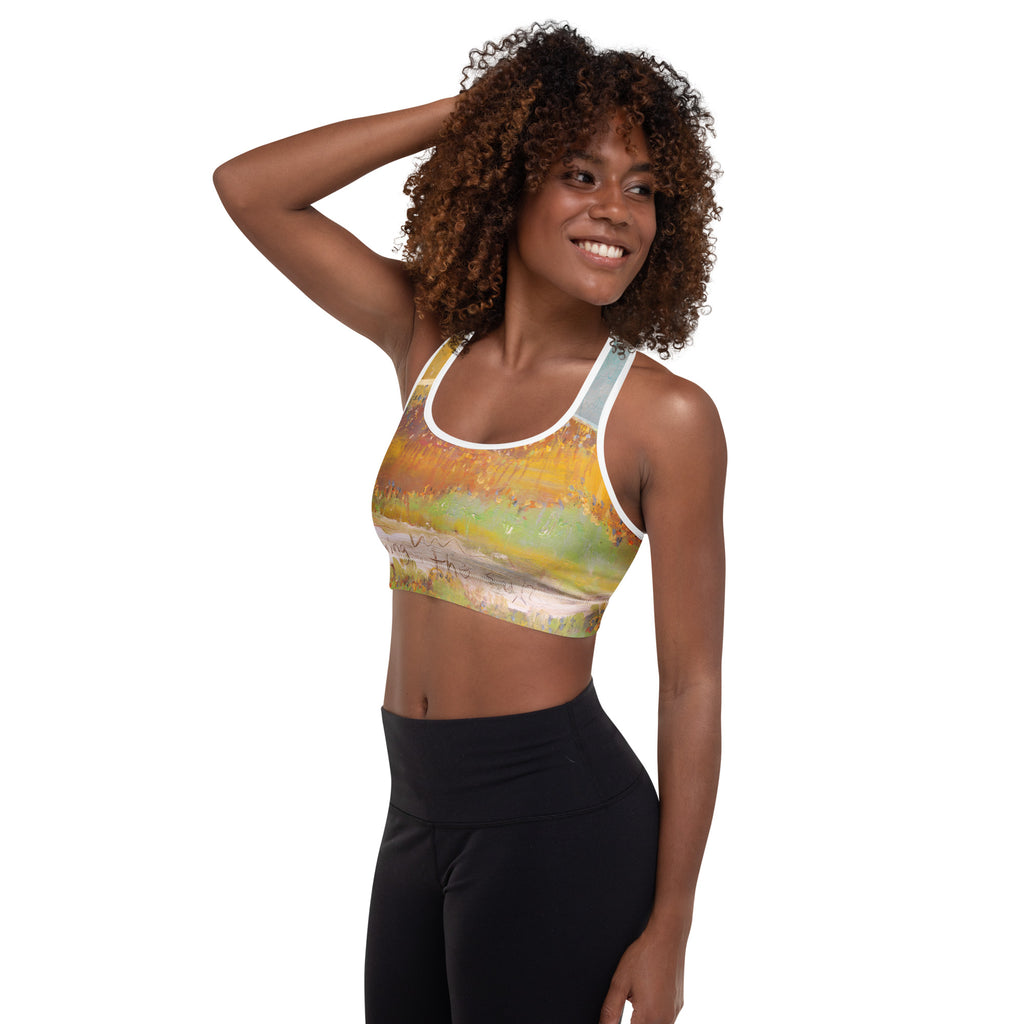 Model with hand in her curly hair, sports bra with ochre drips and a green band