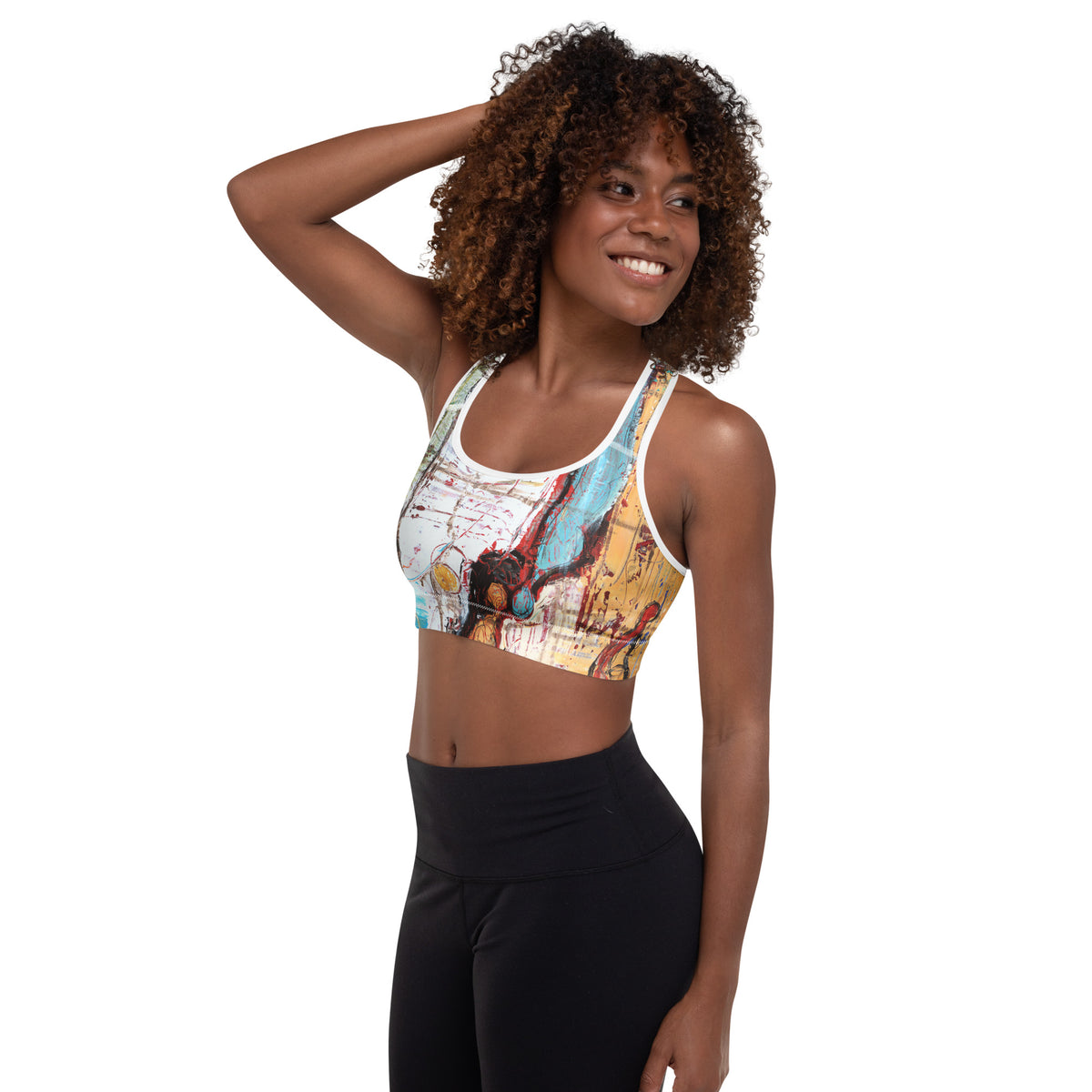 Model with hand in her curly hair smiling sideways, sports bra with blue and red strokes