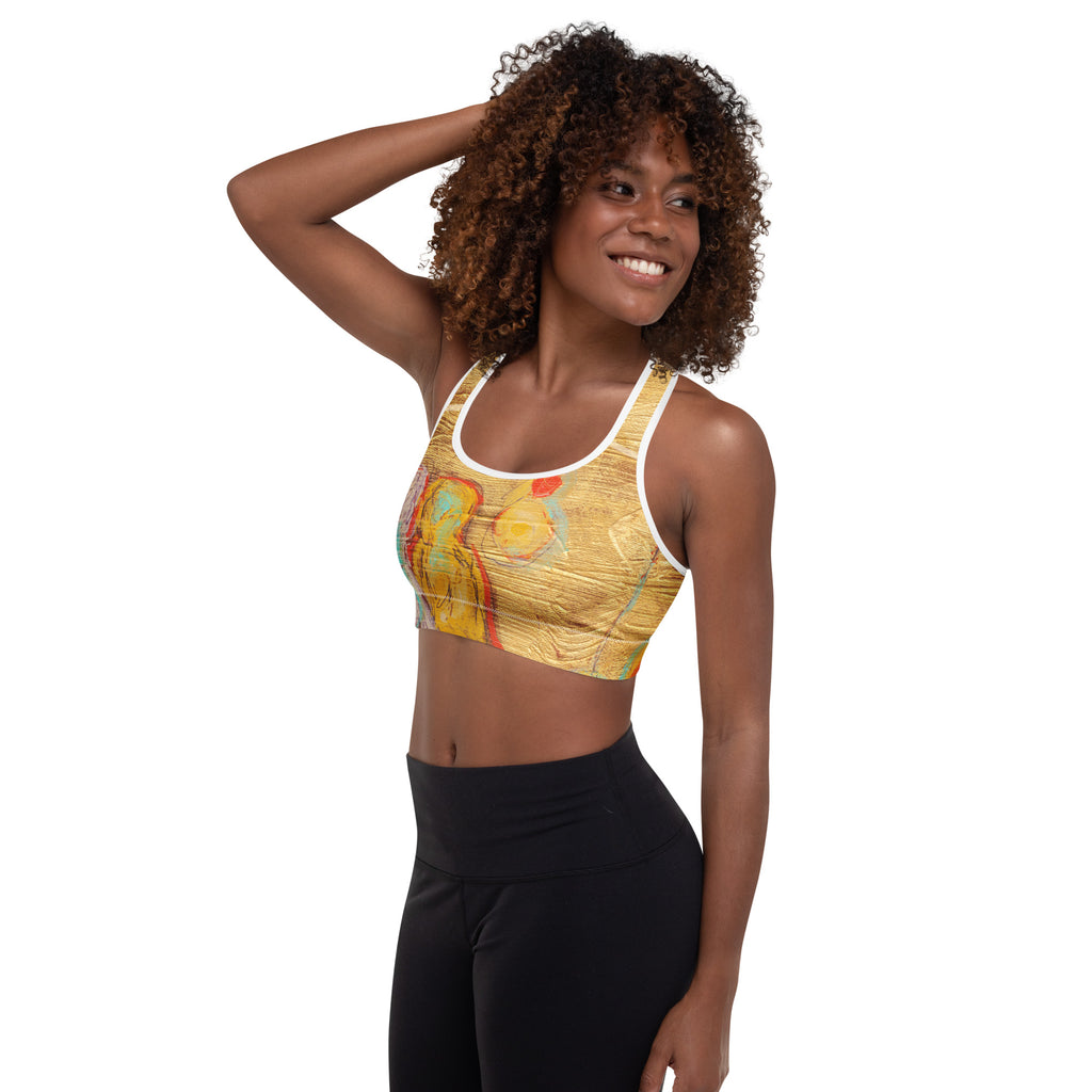 Model with one hand in her hair, angled view of the sports bra showing a yellow figure and orb