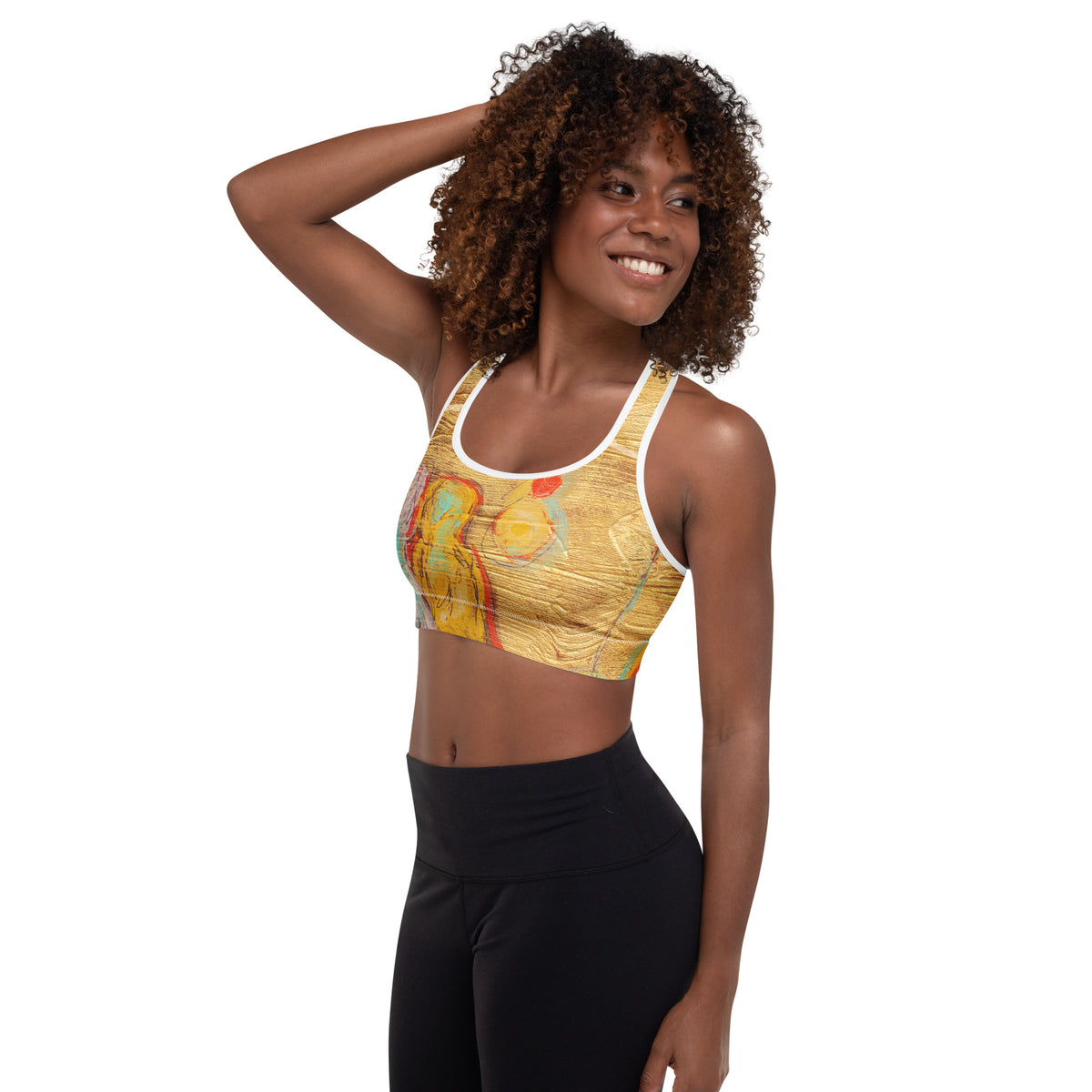 Model with one hand in her hair, angled view of the sports bra showing a yellow figure and orb