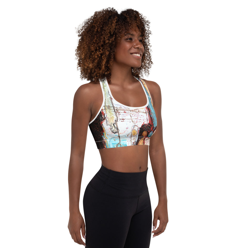 Three-quarter view of smiling model in the sports bra, white front with gold circles