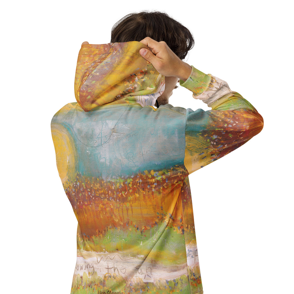 Back view of a model pulling up the hood of the FOLLOWING THE SUN zip hoodie, turquoise sky and amber meadow across the back