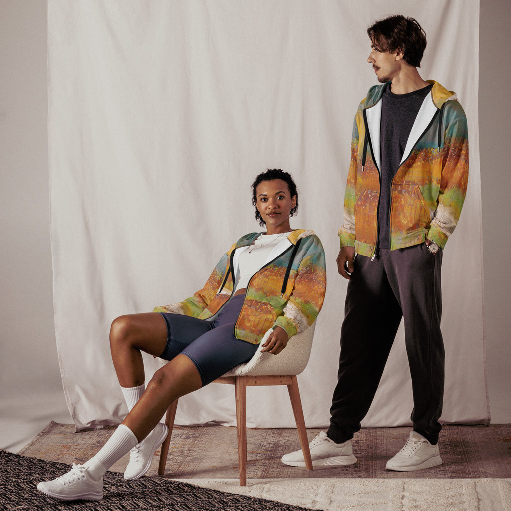 Two models in open FOLLOWING THE SUN zip hoodies, one seated on a chair and one standing, in a studio setting