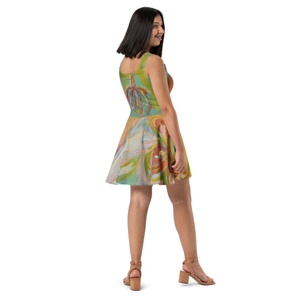Back three-quarter view of model in the dress and tan sandals, rust flower shapes on the turquoise back