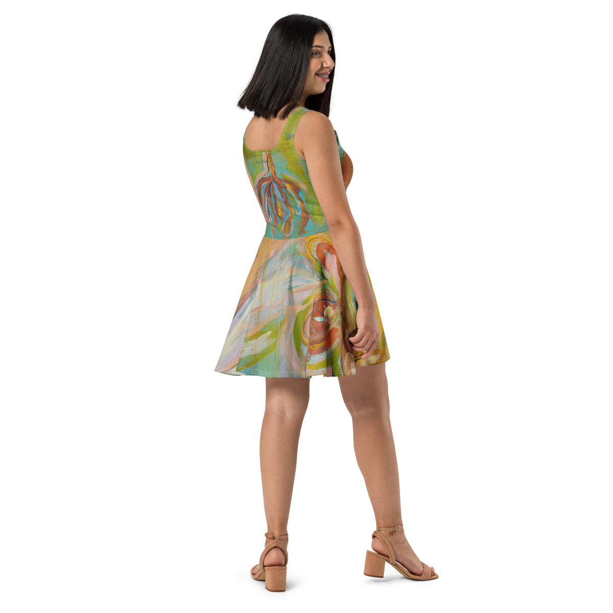 Back three-quarter view of model in the dress and tan sandals, rust flower shapes on the turquoise back