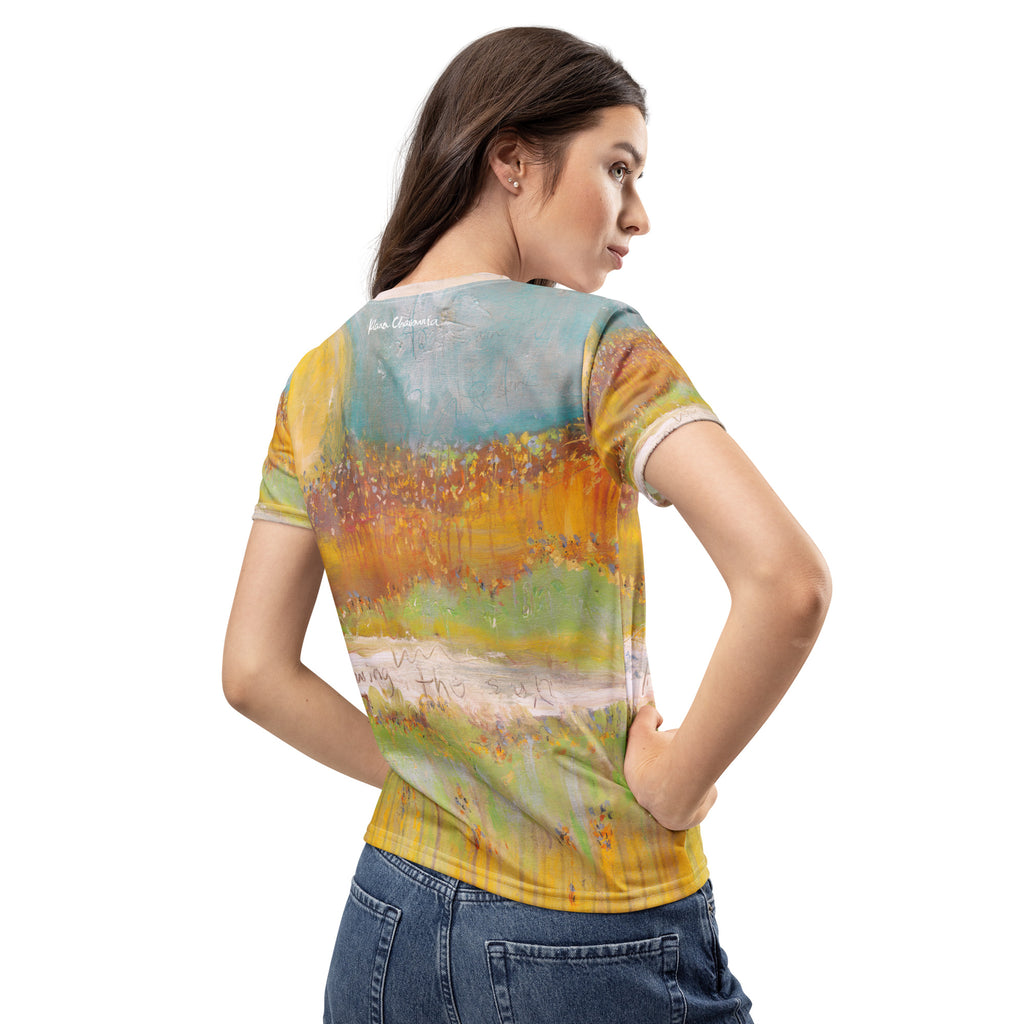 Back view of dark-haired model with hand on hip, signature near the collar of the tee