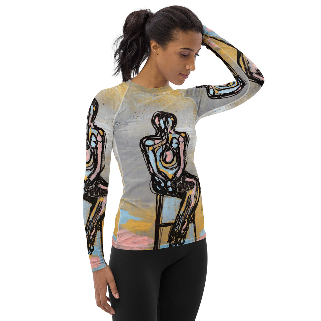 Model with one hand on her head in the rash guard and black leggings, looking down