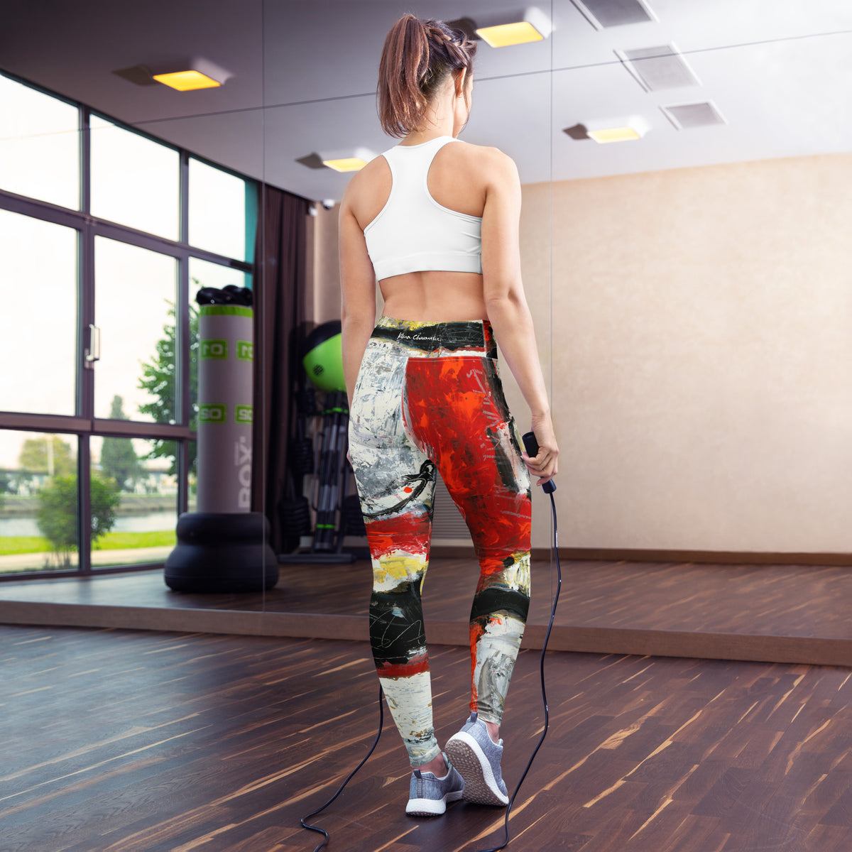 Model with a ponytail from behind holding a jump rope in a gym with mirrors