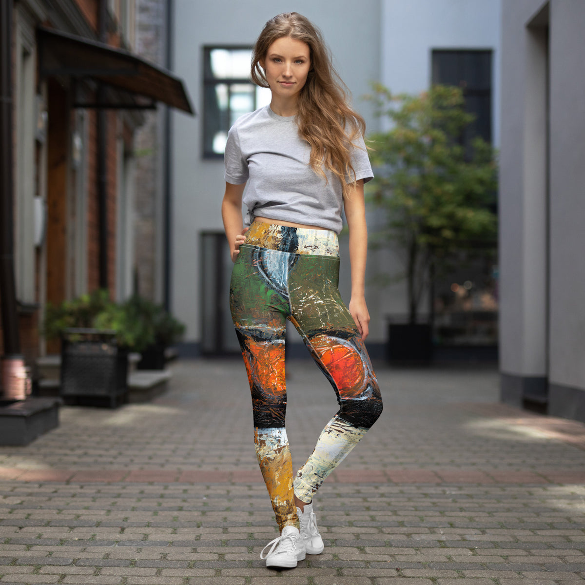 Model in a gray tee and white sneakers wearing the leggings on a brick courtyard street