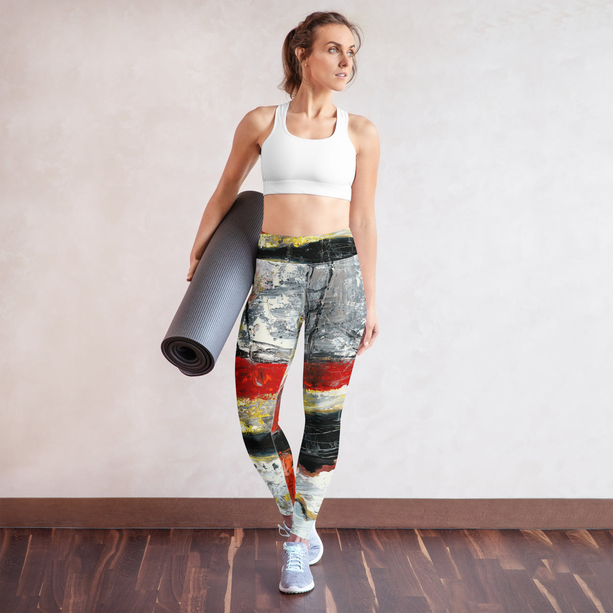 Model in a white sports bra holding a rolled yoga mat, leggings in front view