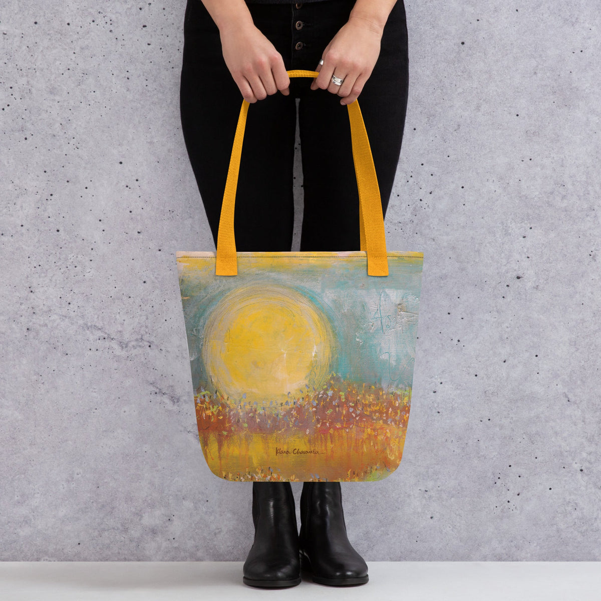 FOLLOWING THE SUN tote bag in Yellow – front held against concrete