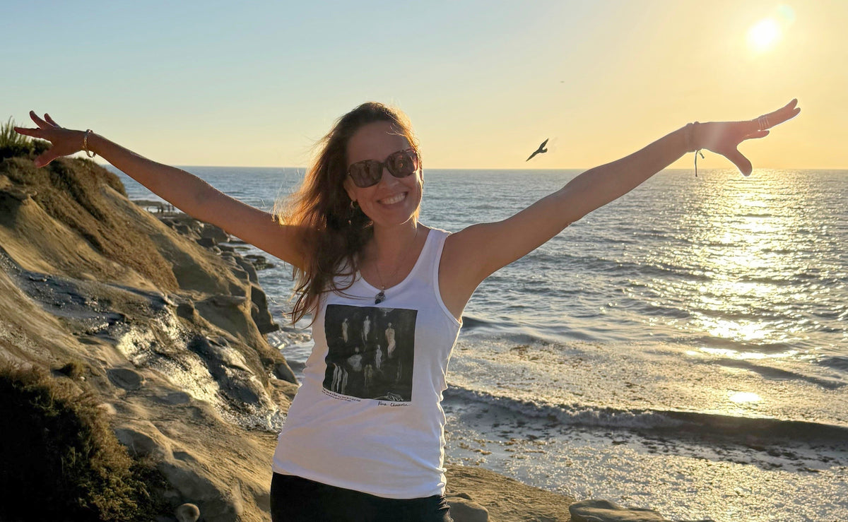 Klara Chavarría smiling with arms outstretched on the La Jolla coast at sunset, the Pacific Ocean behind her