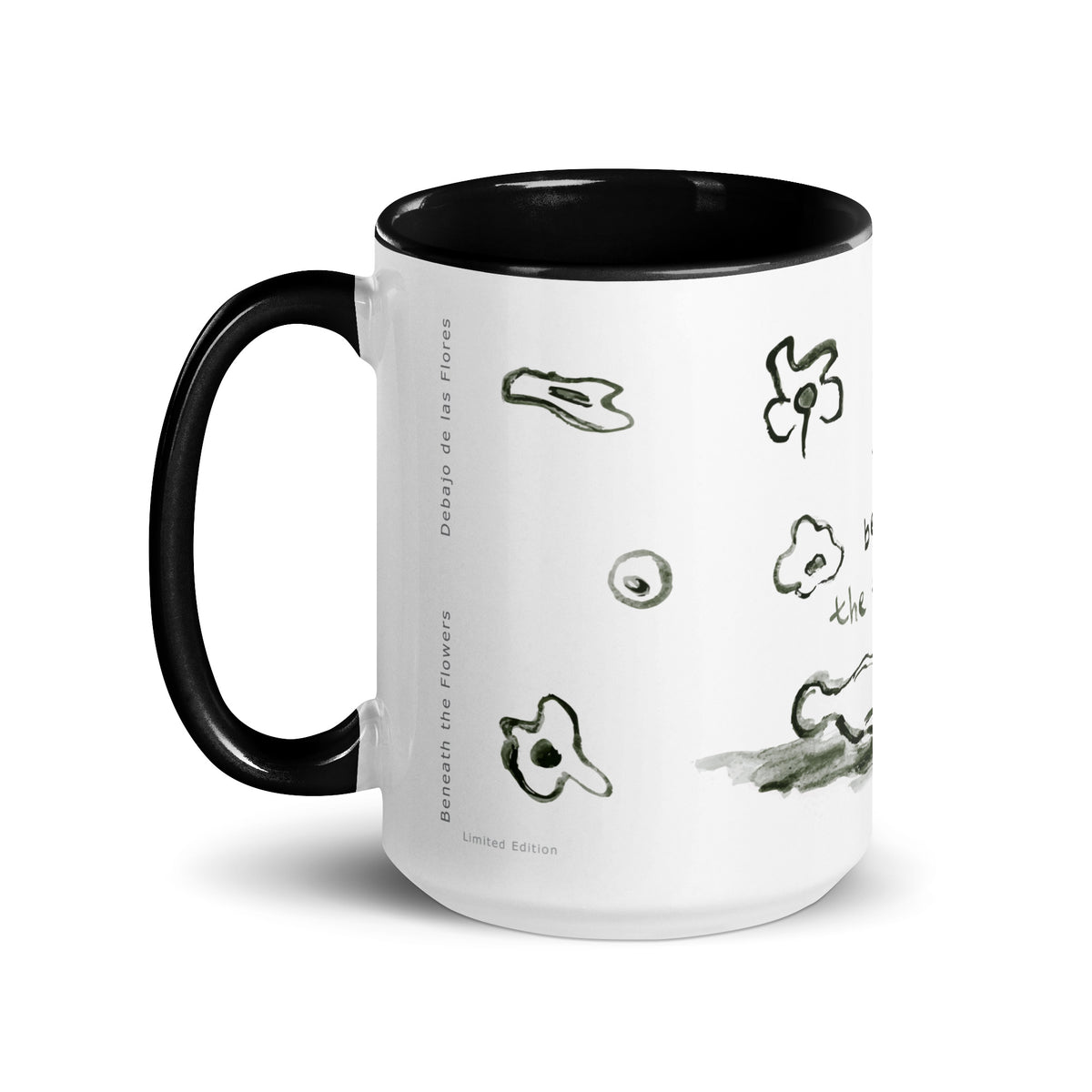 Mug with handle on the left, showing ink flower doodles and the printed titles Beneath the Flowers and Debajo de las Flores