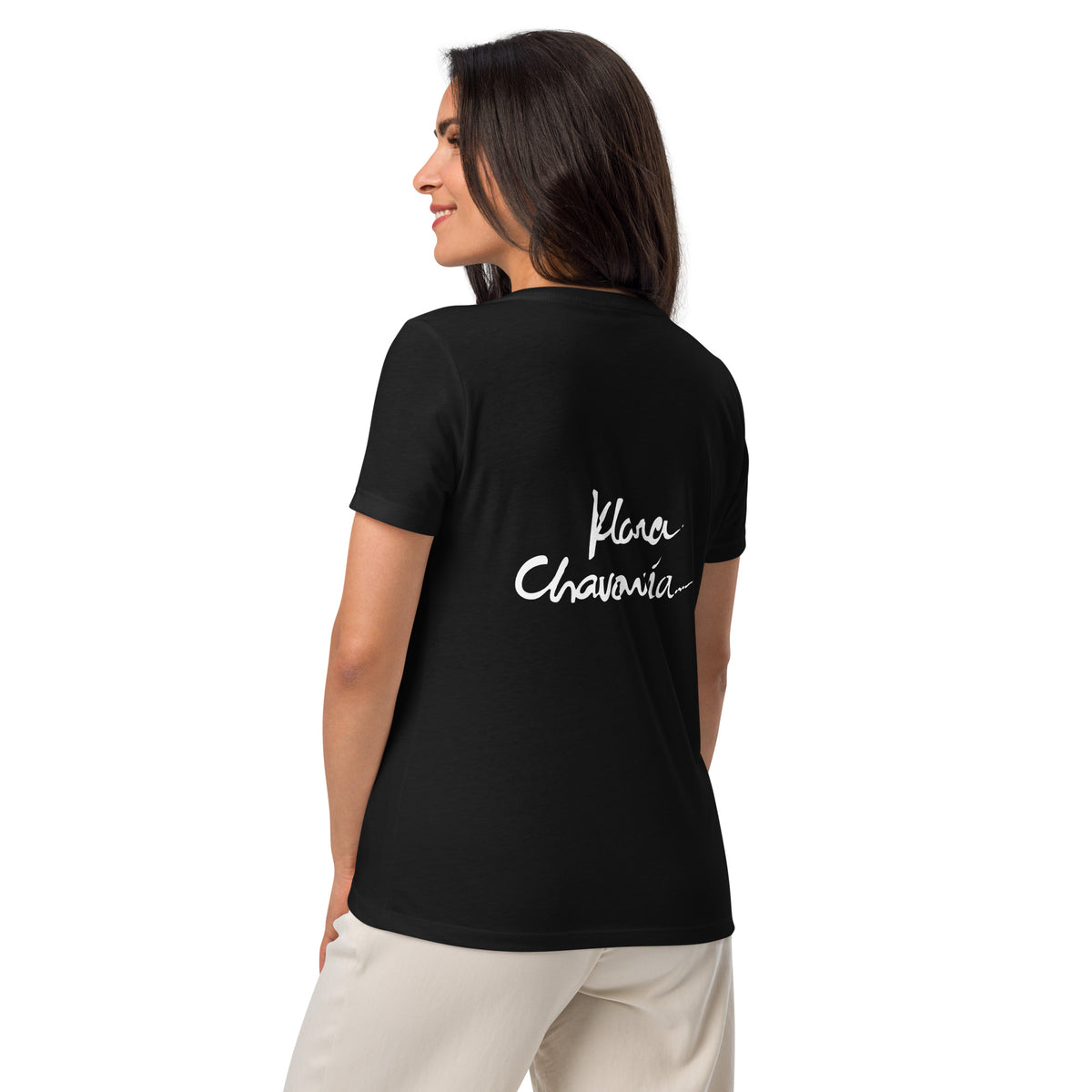 Back view of model in the black V-neck tee and cream trousers, large white handwritten signature on the back